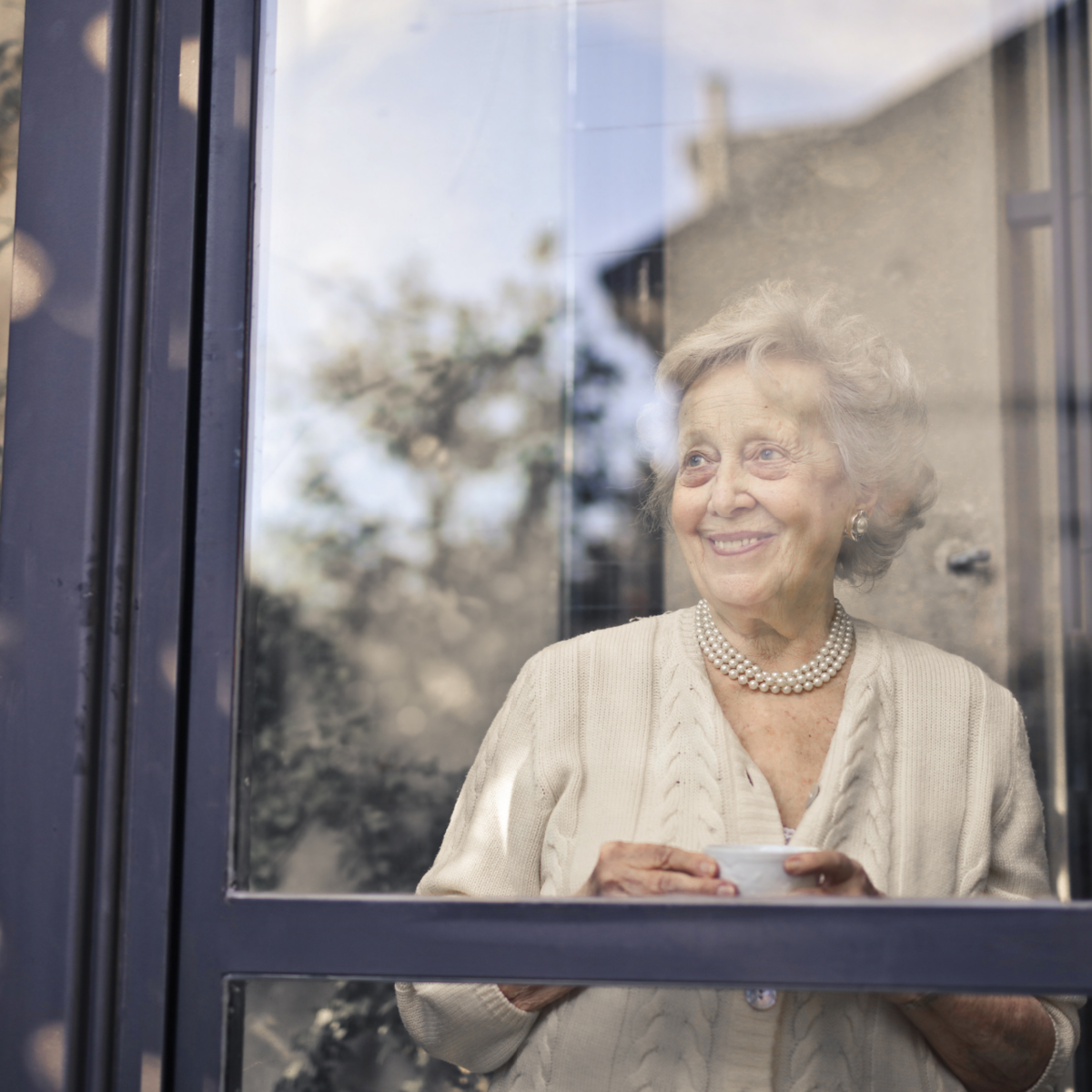 Senior woman looking at the window as she drinks her tea